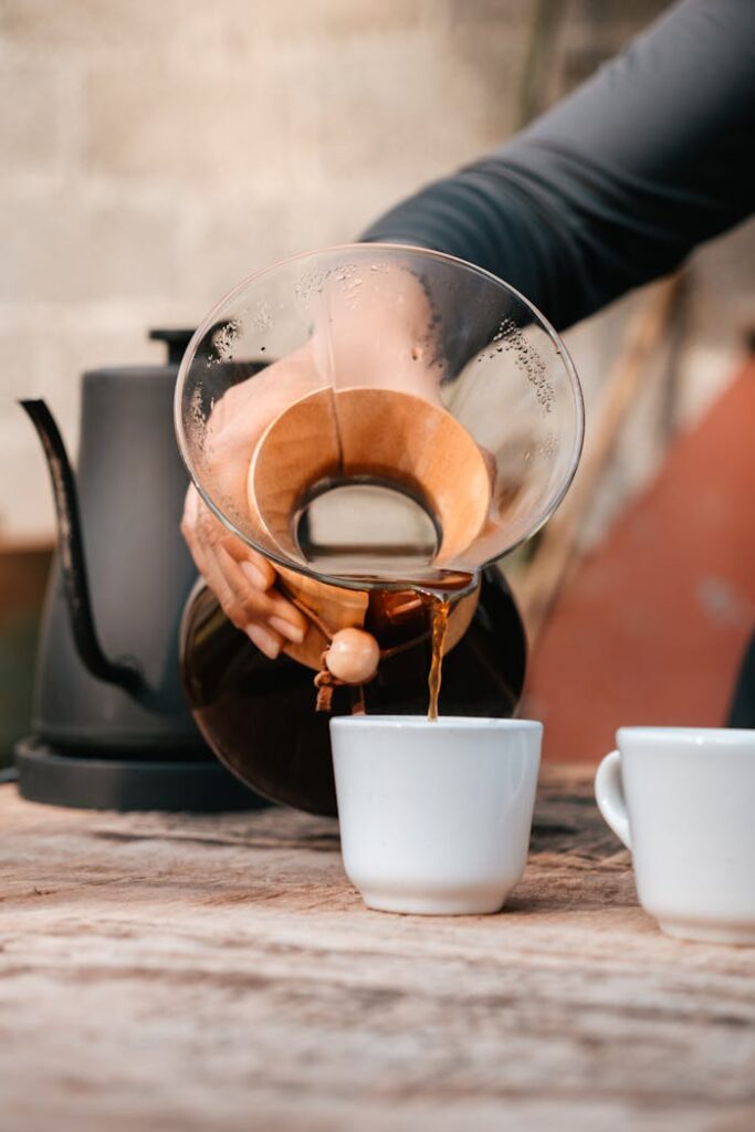 Close-up of hand pouring coffee from a Chemex into a cup outdoors in Xicotepec, Puebla, México.